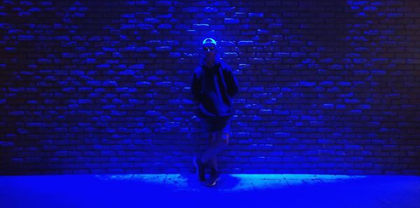 Full length of woman walking against illuminated wall