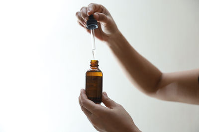 Cropped hand holding bottle against white background