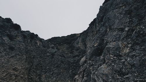 Low angle view of rocky mountains against clear sky