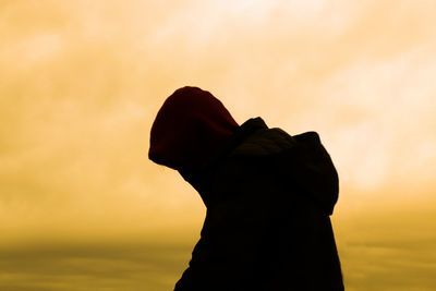 Silhouette man standing against orange sky