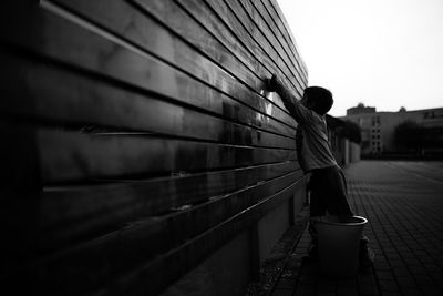 Boy cleaning wooden wall