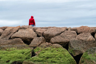 Rear view of man on rock against sky