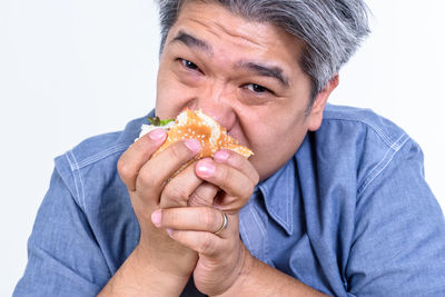 Portrait of man holding ice cream against white background