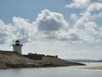 Lighthouse by sea against sky