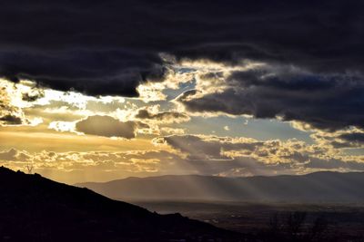 Scenic view of dramatic sky over silhouette mountains