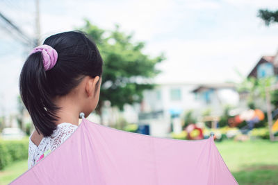 Rear view of girl with umbrella standing at park