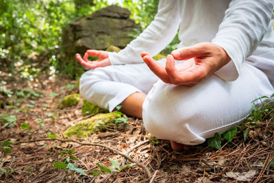 Midsection of person doing yoga on field