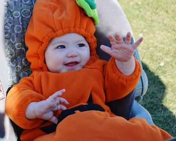 High angle view of baby in pumpkin costume relaxing on carriage