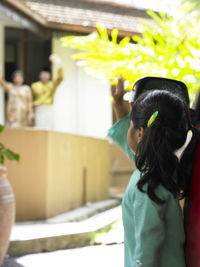 Grandparents waving at granddaughter while standing outside house