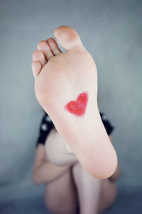 Close-up of woman with heart shape drawing on foot