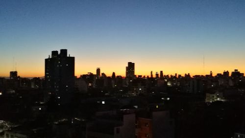 Illuminated buildings in city against clear sky