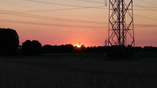 Silhouette trees on field against sky at sunset