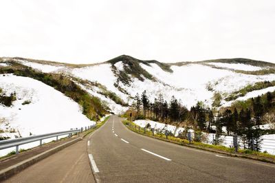 Empty road leading towards snowcapped mountains