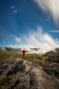 Rear view of man standing on rock against sky