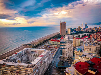 High angle view of buildings by sea against sky during sunset