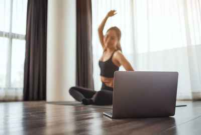 Full length of woman using mobile phone while sitting at home