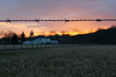 Close-up of barbed wire against sky during sunset