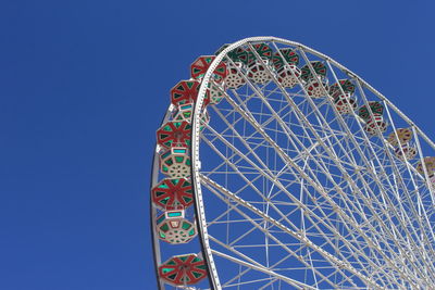 Low angle view of ferris wheel against clear sky on sunny day