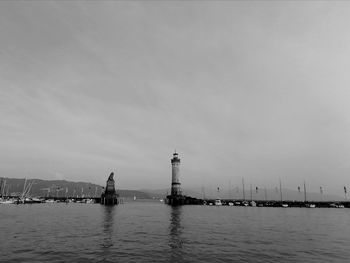 Silhouette of buildings by sea against sky