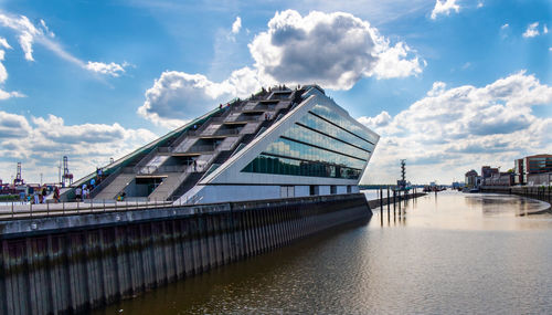 Bridge over river by buildings against sky