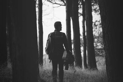 Rear view of woman standing on tree trunk