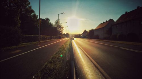 Road amidst trees against sky during sunset