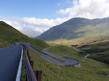 Scenic view of road by mountains against sky