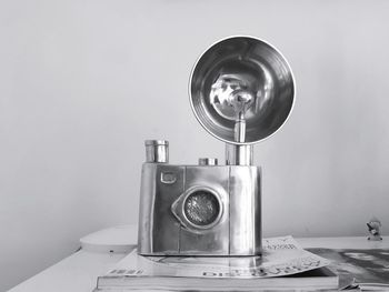 Close-up of old camera on table against wall