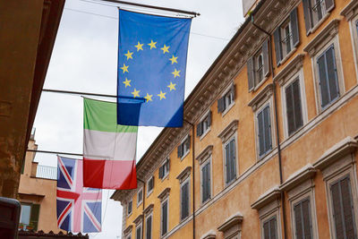 Low angle view of flags hanging by building