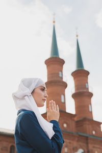 Young woman standing outside temple against building