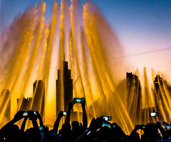 Low angle view of people photographing fountain from mobile phones