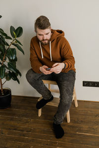 Side view of young woman sitting on hardwood floor