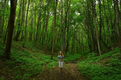 Full length of man standing on tree trunk in forest