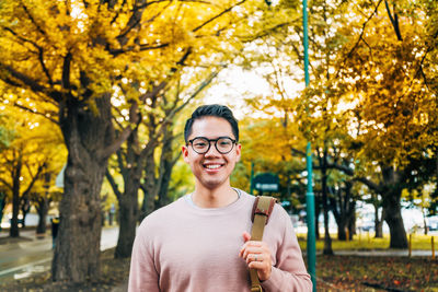 Portrait of smiling young man standing by plants during autumn
