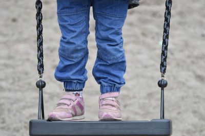 Low section of girl standing on swing