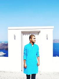 Young man standing against blue sky