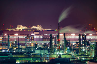 Illuminated factory against sky at night