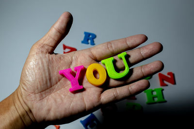 Close-up of hand holding multi colored text