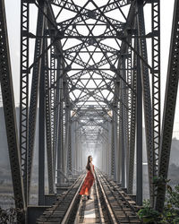 Rear view of woman standing on railroad bridge