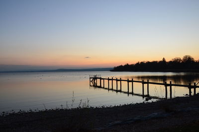 Scenic view of lake against clear sky during sunset