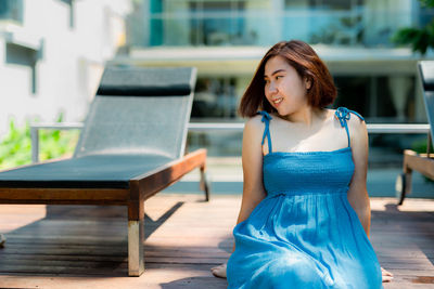 Portrait of a young woman sitting on swimming pool