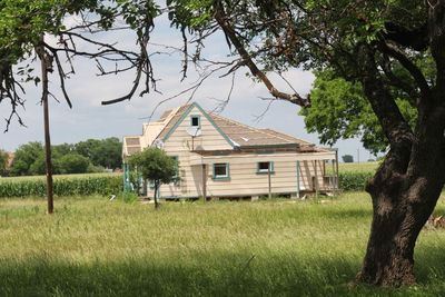 House on field by trees against sky