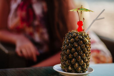 Close-up of pineapple on table with woman in background