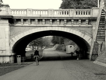 Woman walking on road by bridge against sky