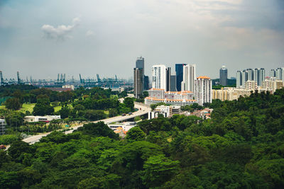 Trees and buildings in city against sky