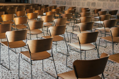 Set of empty wooden chairs lined up in an ancient church or castle with medieval floor and walls.