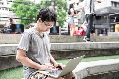 Rear view of senior woman using mobile phone while sitting outdoors