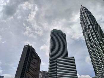 Low angle view of skyscrapers against cloudy sky