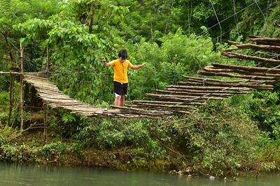 Rear view of woman walking on footbridge