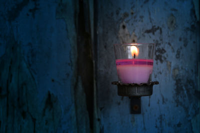 Close-up of illuminated lamp against wall